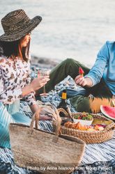 Couple having picnic by the ocean with man holding strawberry 47kZg4