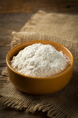 Bowl with wheat flour on the table.