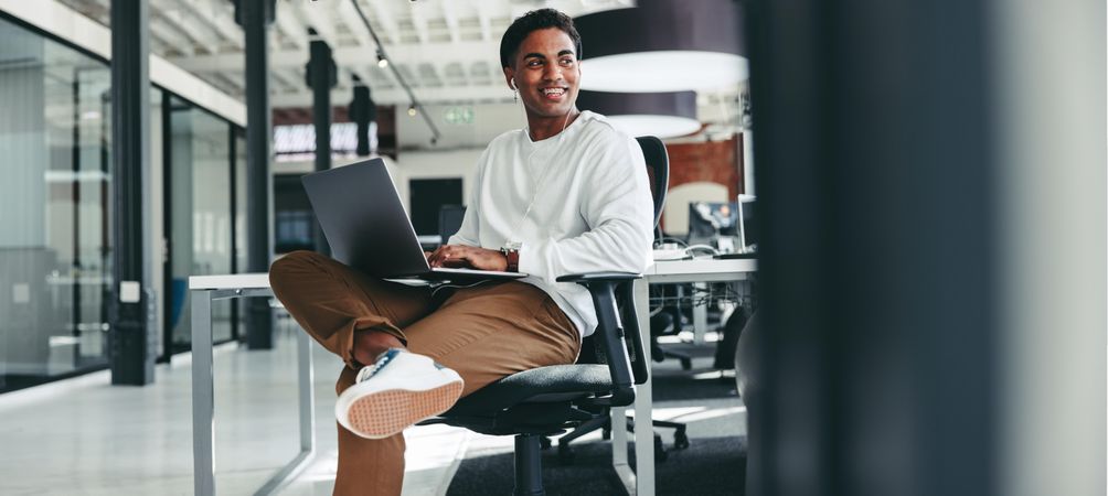 Happy stylish young male programmer smiling while working