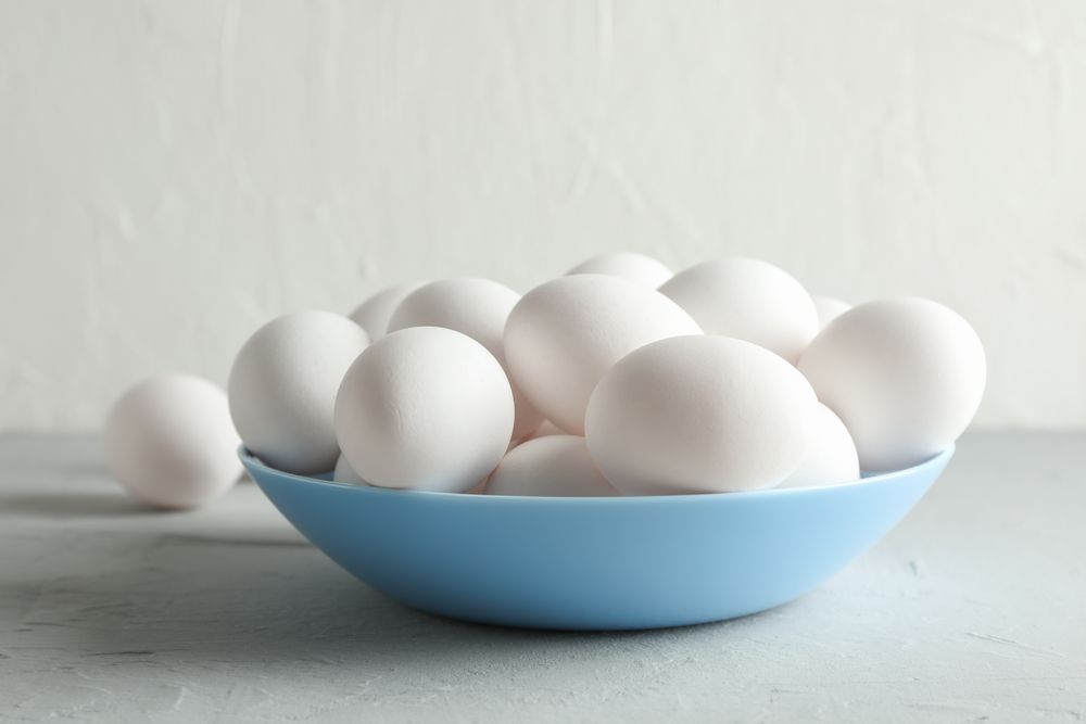 chicken eggs in plate on grey table against light background, space for text