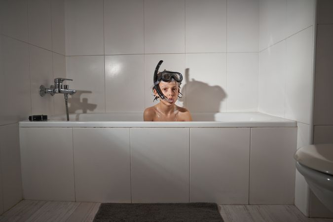 Boy in snorkeling mask sitting in bathtub