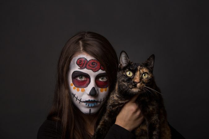Young woman with creepy face paint holding cat