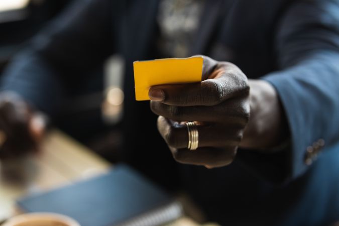 Anonymous crop Black executive with business card in cafe