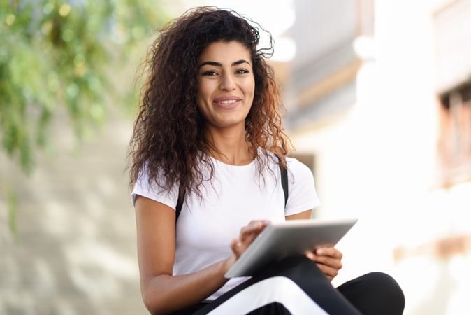 Content Arab woman with her digital tablet sitting outdoors
