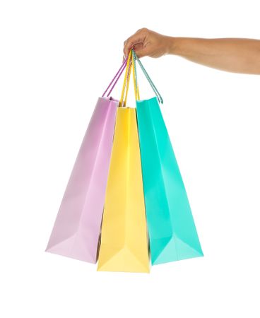 Female hand hold color paper bags isolated on blank background