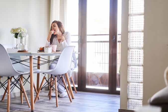 Smiling woman eating at table at home