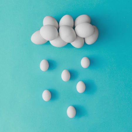 Cloud and rain made of eggs on blue background