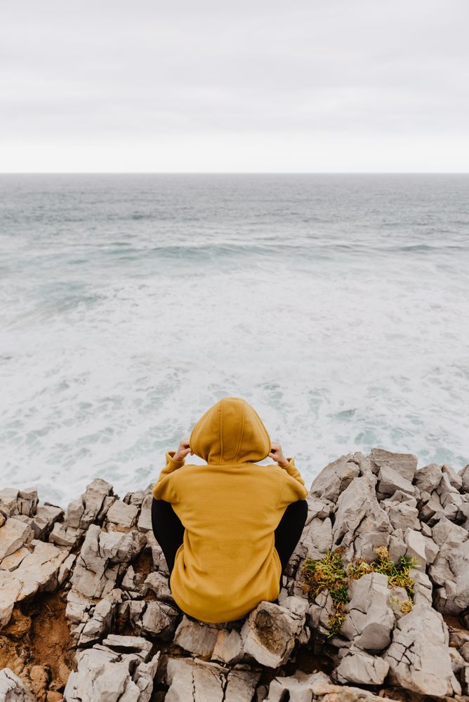 Person in yellow hoodie on stony shore