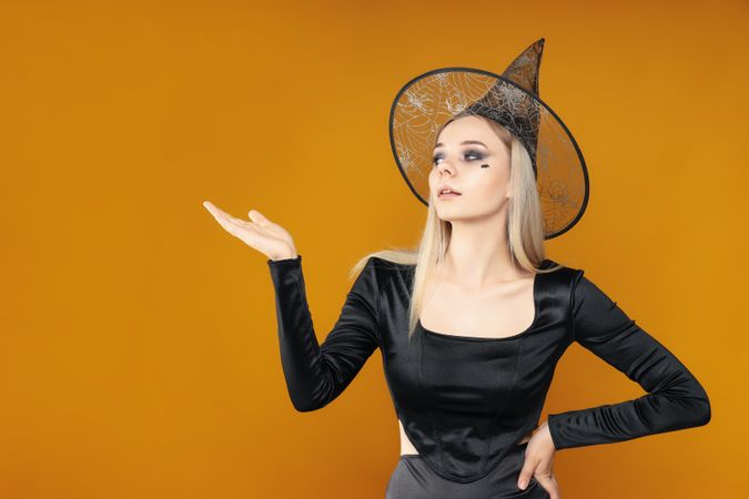 Concept of Halloween, young woman on yellow background