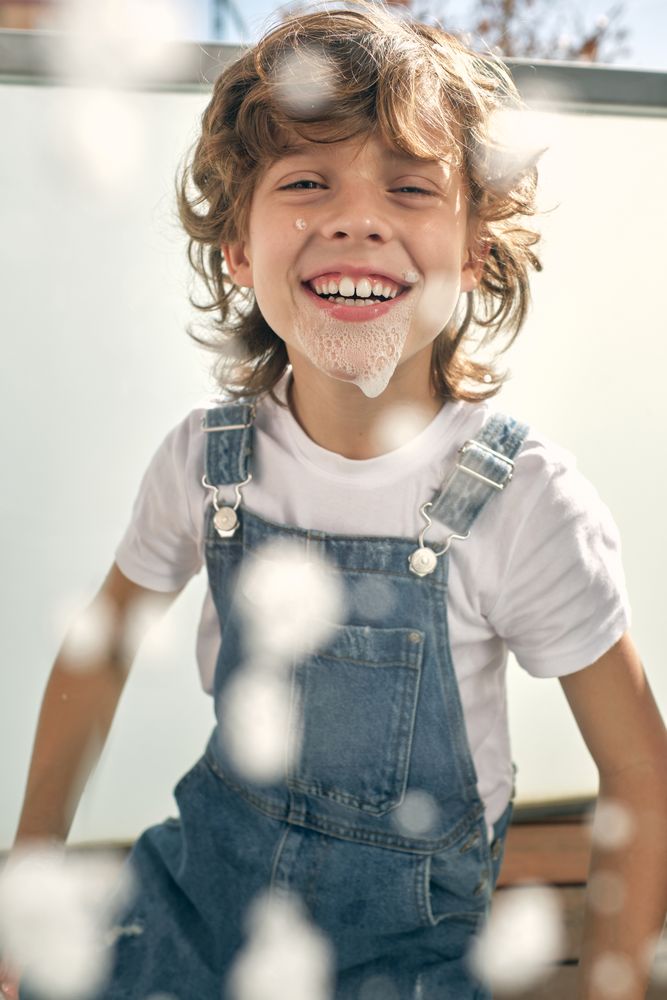 Cheerful boy playing with foam during cleaning