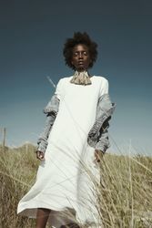 Woman in light dress and denim jacket standing on brown grass