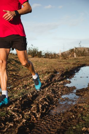 Sportsman running on dirty road in countryside