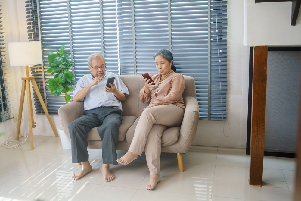 Older couple using smartphones on couch