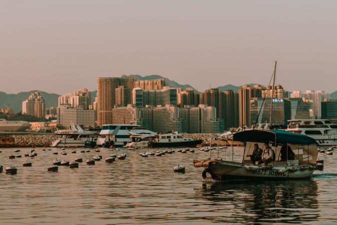 People on boat near city at sunset