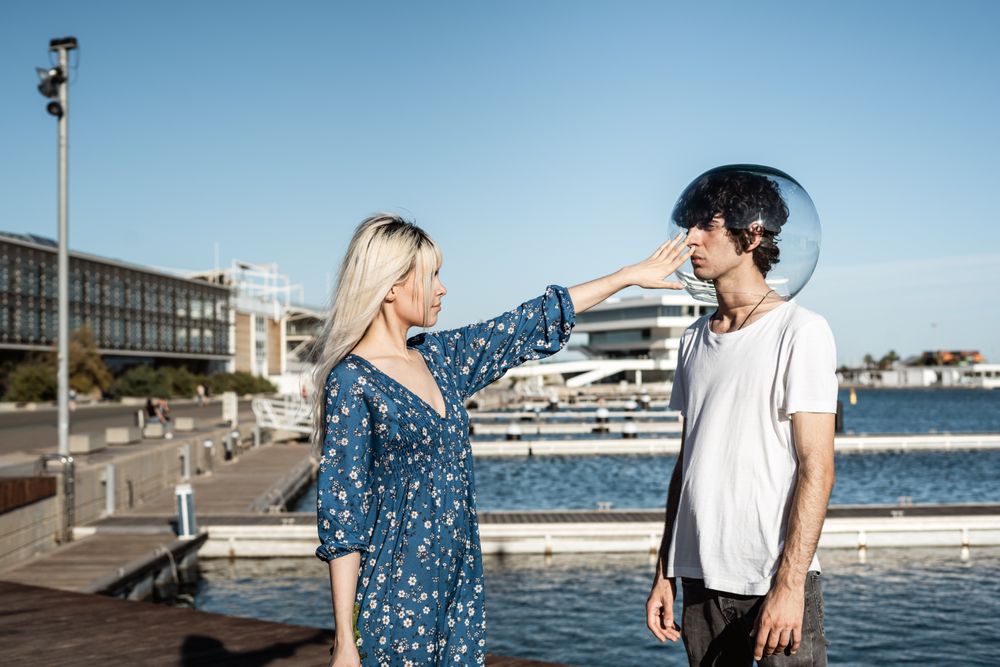 Woman touching fish bowl on head of boyfriend