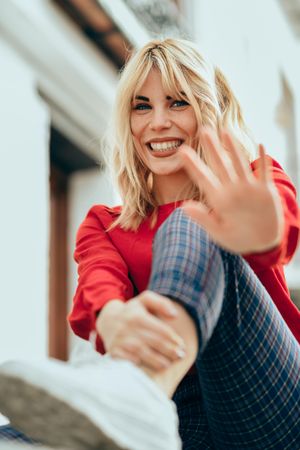 Playful blonde female with red shirt with palm out to camera, vertical