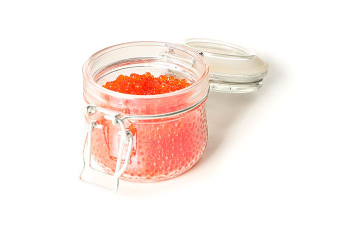 Glass jar with caviar isolated on plain background