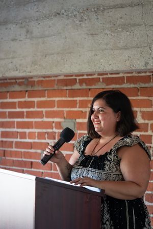 Woman holding a microphone and smiling at the podium