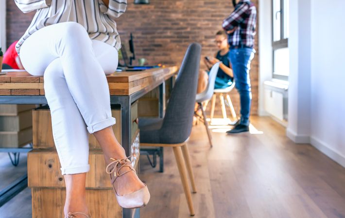 Unrecognizable businesswoman sitting on table in the office