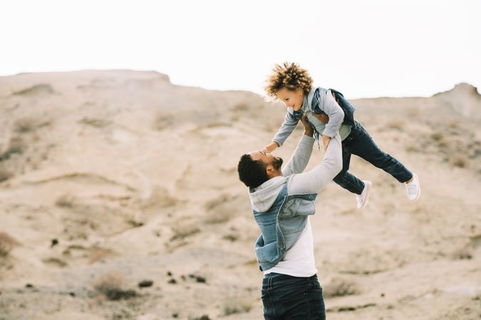 Black father playing with child on ground
