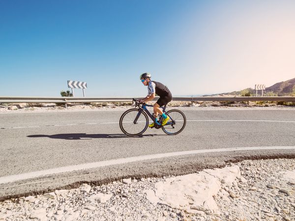 healthy man riding a bicycle on a mountain road in a sunny day