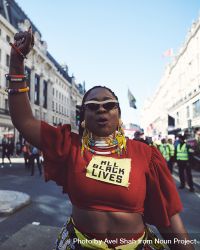London, England, United Kingdom - March 19 2022: Black woman in African jewelry and raised fist 0yn2q5