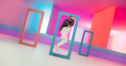Young And Athletic B-Boy Breakdancing To Break Beats in a Colorful Abstract Neon Lit Studio. Energetic Fashionable Male Dancer Talentedly Performing His Choreography On Multicolored Set.