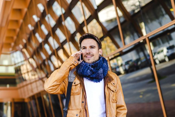 Stylish guy using smartphone outside modern building