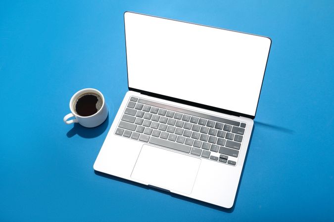 Looking down at blue room with laptop with mock up screen with cup of coffee