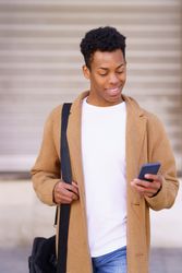 Content Cuban male walking outside holding his phone