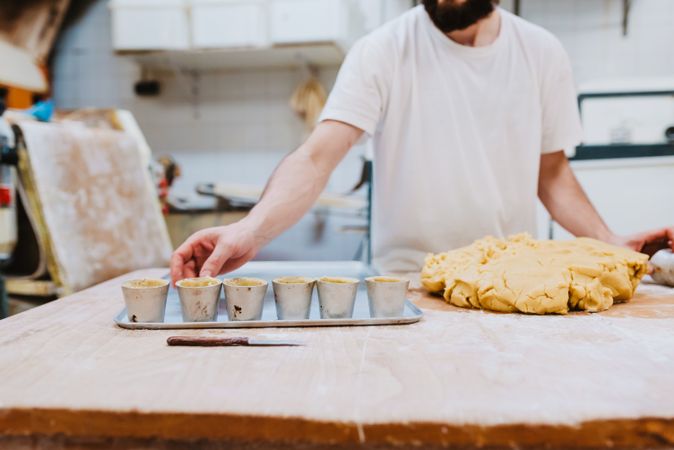 Bearded confectioner putting dough into cup