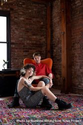 Portrait of young couple sitting together in loft with exposed brick looking at camera 41lNZ5