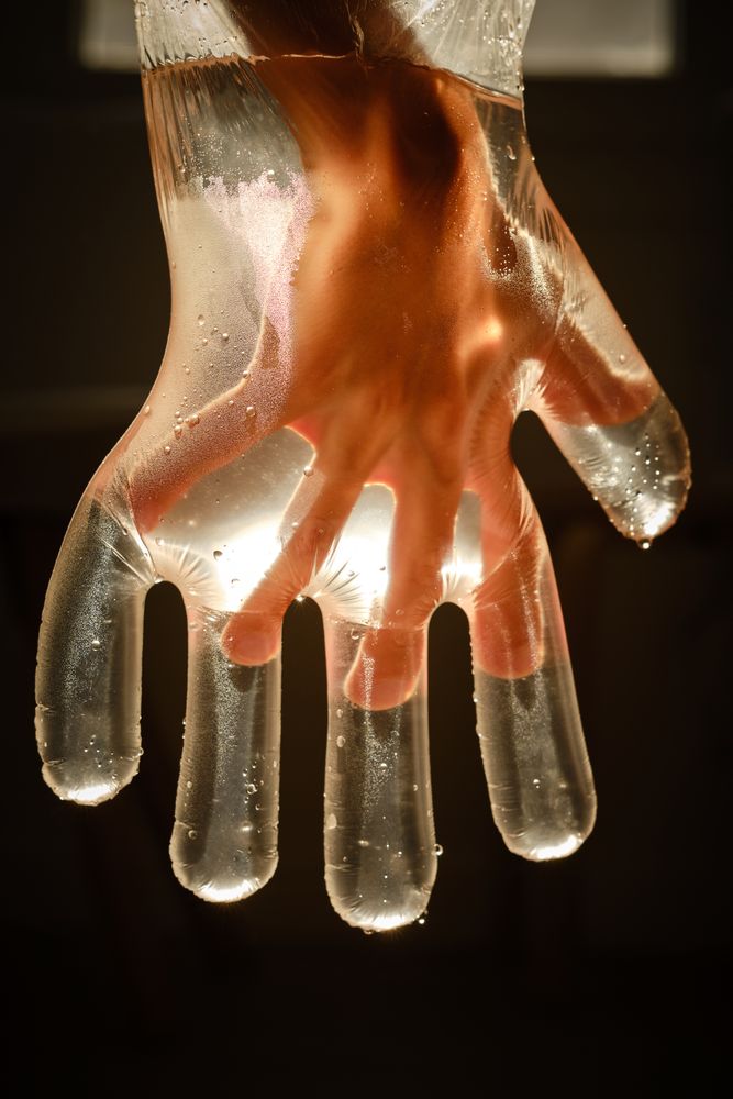 Faceless child in disposable glove with shiny water