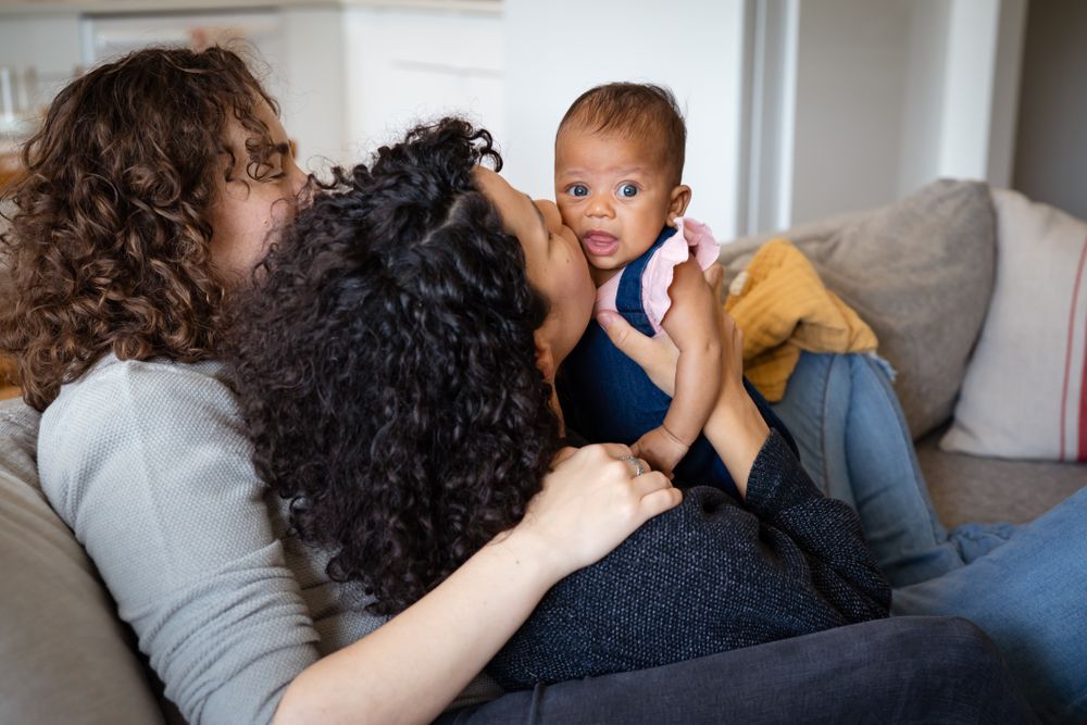 Moms on sofa kissing new baby