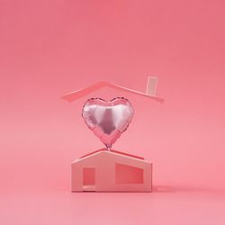 Pink heart balloon above minimalistic house