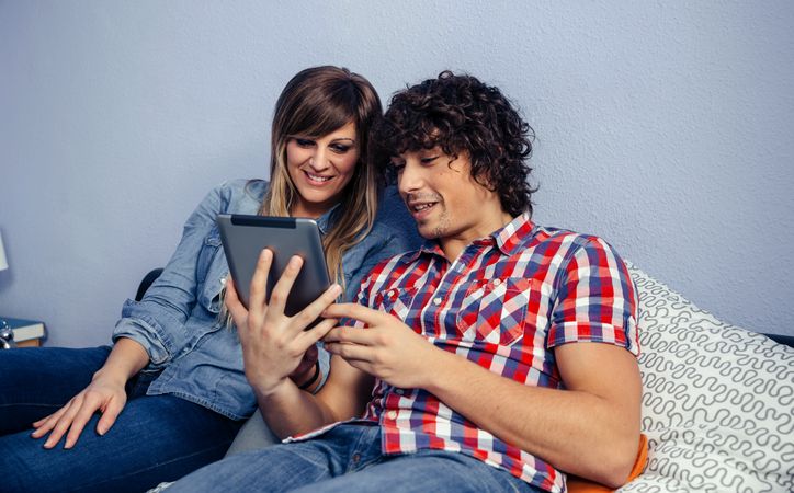 Couple looking at the tablet relaxing in bed