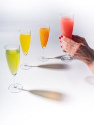 Hand and glasses of bright colorful drinks on table