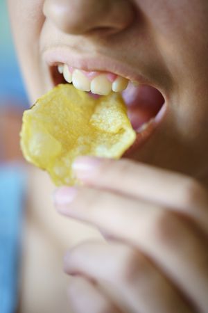 Close up of teenager biting into potato chips