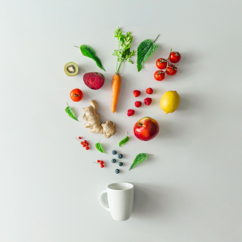 Neatly arranged fruits, vegetables and herbs and light mug on bright table background