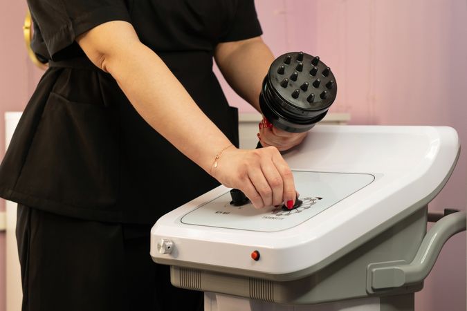 A spa professional adjusting the handheld cavitation device settings