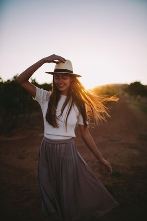 Young woman wearing a hat smiling at sunset