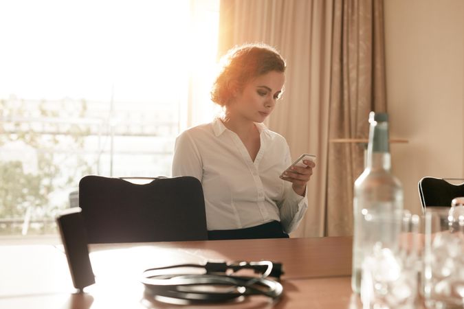 Female executive sitting in a hotel conference room using cell phone