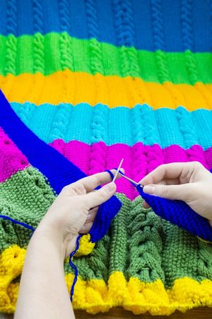 Woman knitting colorful piece of clothing