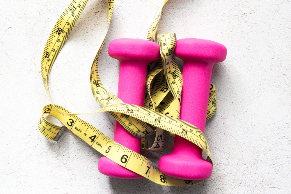 Dumbbells and Measuring Tape on Fitness-Inspired Background
