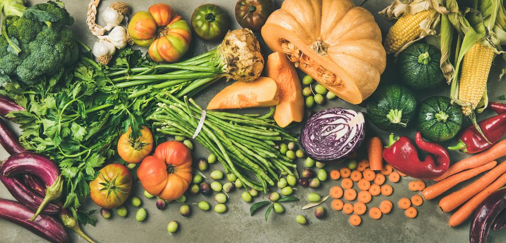 Fresh produce on concrete background, with halved squash, corn, cabbage, wide composition