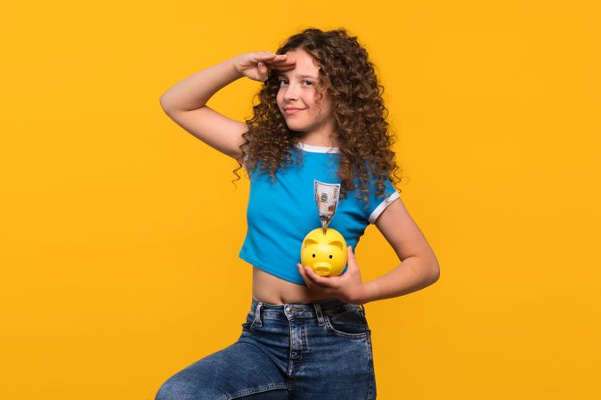 Girl holding a piggy bank and saluting