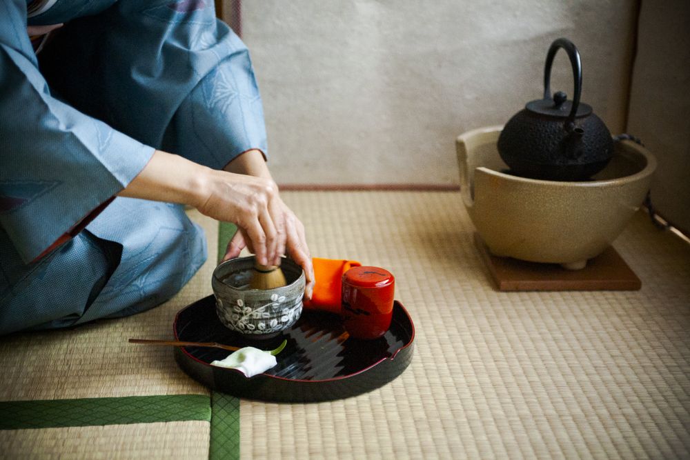 Japanese woman in kimono sitting on ground preparing tea