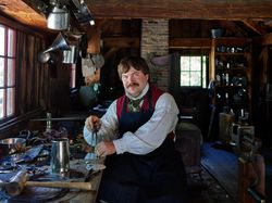 Costumed interpreter at work as a tinsmith at Old Sturbridge Village, Sturbridge, Massachusetts y0PJe4