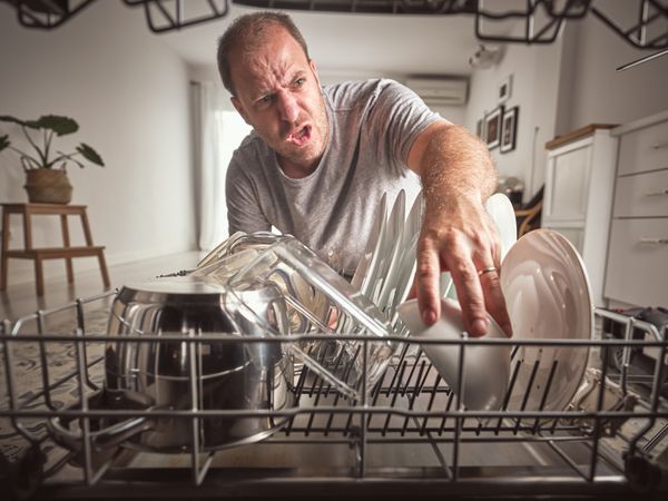 Angry man unloading modern dishwasher