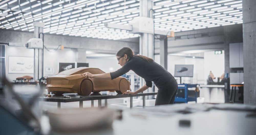 Female Car Modeler Enjoying Creative Work Process on a Concept Car Made Out of Plasticine Modeling Clay.